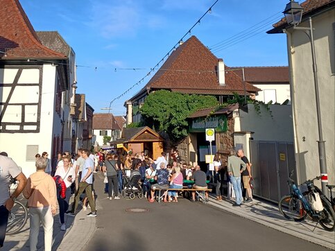 Diedesfelder Kerwe – Weinfest im Ortskern von Diedesfeld Besucher der Diedesfelder Kerwe an Tischen und Ständen in einer Dorfstraße mit Fachwerkhaus und Lichterketten